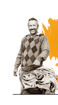 Schwarz-weiß Foto von Bauer Gruenauer mit einem Korb in der Hand. Im Hintergrund ist orangene Farbe. | © SONNENTOR