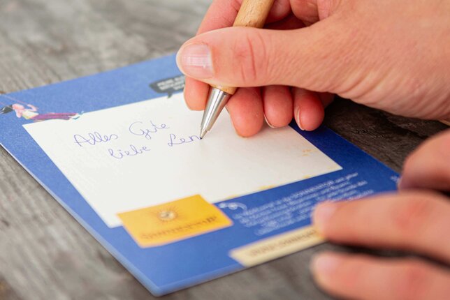 Ein Sonnentor-Mitarbeiter schreibt eine Grußkarte per Hand. | © SONNENTOR