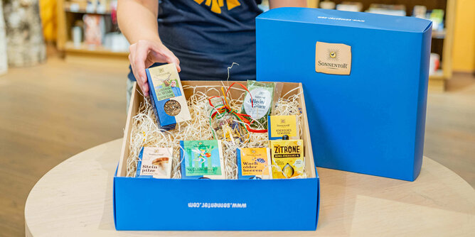 Ein blauer Geschenkkarton ist befüllt mit einigen Produkten.  | © SONNENTOR