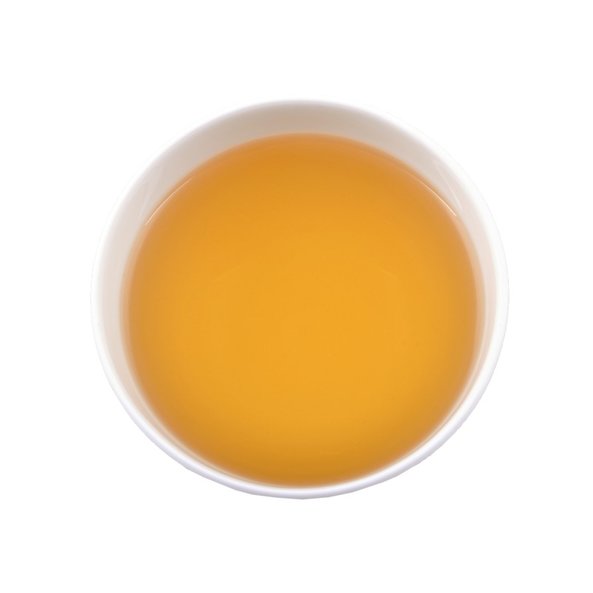 Photo of a cup with brewed SONNENTOR Darjeeling black tea loose, which shimmers in a golden maroon colour.