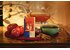 Photo of a pack of Fireplace Fruit Tea, a teapot, a dark green cup of tea, three red apples, two star anisees and four cinnamon sticks.