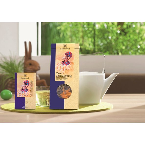 Photo of a pack of Easter surprise tea loose, Easter surprise double chamber bag, a white teapot and a cup of tea.