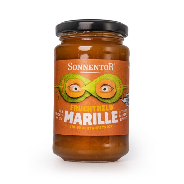 Glass with apricot organic fruit spread. The label shows apricot halves with eyes on leaves that look like a superhero mask overall. Note: Sweetened with concentrated apple juice. 60% fruit content.