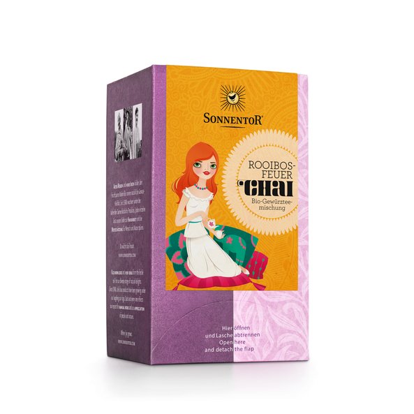 Eine lila Packung Chai Rooibosfeuer Tee. Auf der Verpackung ist ein Mädchen zu sehen das auf einem Kissen sitzt und Tee trinkt.