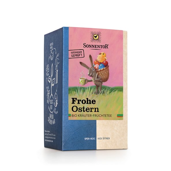 Foto einer Packung Frohe Ostern Tee Bio-Kräuter-Früchteteemischung. Auf der Packung ist eine Illustration mit einem Hasen, der einen Korb mit bunt bemalten Eiern und einem Küken obendrauf auf seinem Rücken trägt und eine dampfende Tasse Tee in seiner Hand hält.