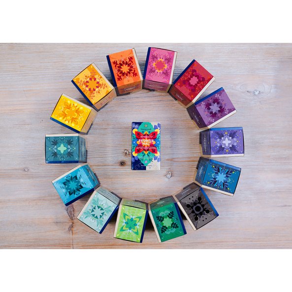 A picture of all Happiness Is varieties. The tea packs are placed in a circle and in the middle of it is the Probier mal pack.
