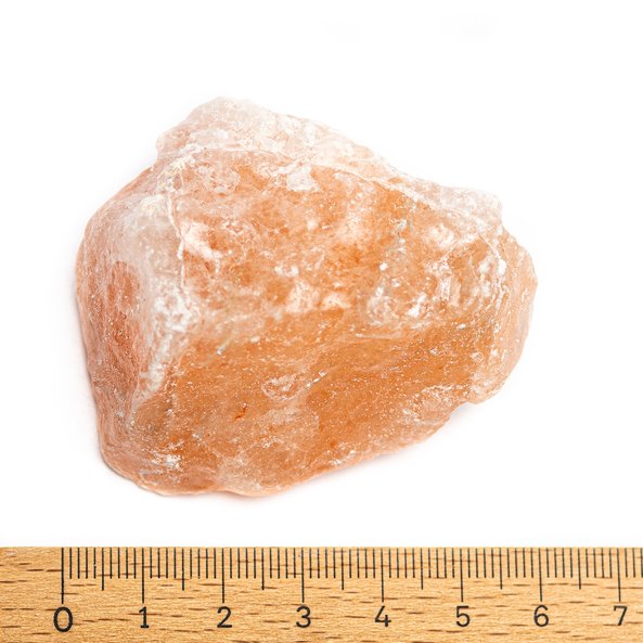 Foto von einem rosa ayurvedischen Salzbrocken. Darunter liegt ein Lineal, sodass man sehen kann, dass der Brocken circa sechs Zentimeter groß ist.
