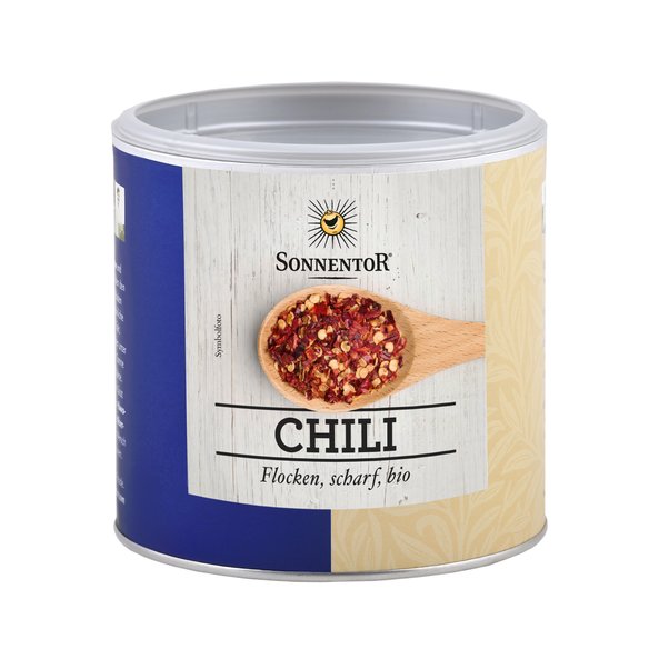 A picture of a small jumbo spice tin chili flakes. On it you can see a wooden spoon with chili flakes.
