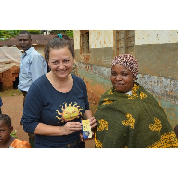 A photo in a village in Tanzania showing several people. A woman is holding a pack of cloves in her hand.