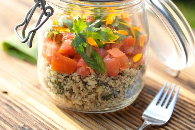 Foto von einem Glas Cous Cous Taboulé Salat auf einem Holztisch. Daneben liegt eine Gabel. | © SONNENTOR