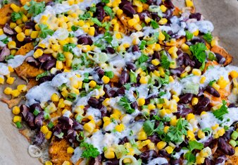  The sweet potato slices are topped with corn, red beans, fresh parsley, spring onion rings and joghurt sauce on a baking sheet. | © SONNENTOR