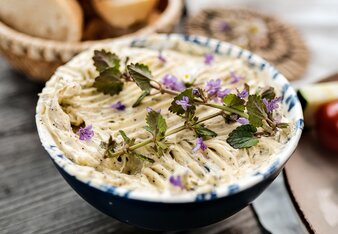 The herb butter is in a bowl decorated with edible flowers. | © SONNENTOR