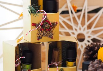 Auf dem Foto sind drei übereinander gestellte Gewürz-Mandala Geschenkboxen zu sehen. Auf dem Foto sind auch Zapfen und Holzsterne zu sehen. | © SONNENTOR