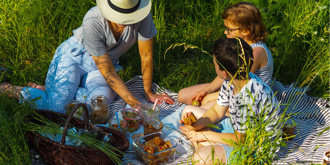 Auf dem Foto sieht man eine Familie beim Picknicken auf einer Wiese. | © SONNENTOR